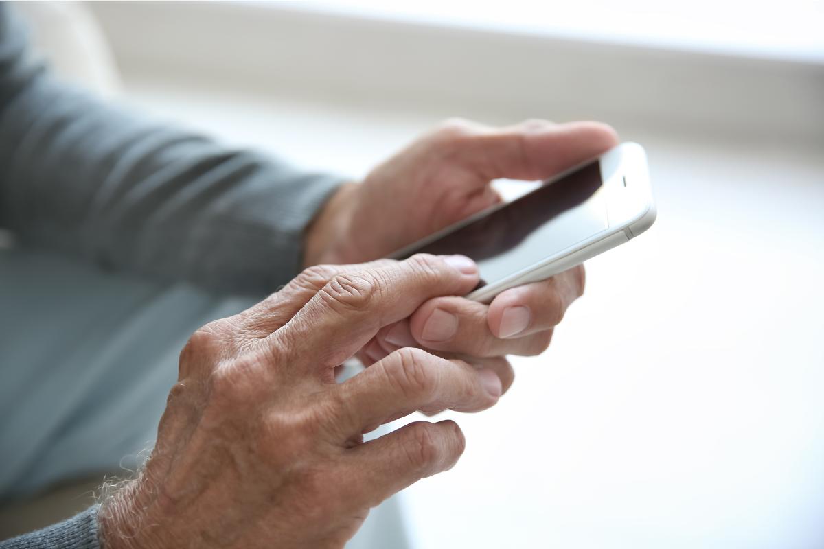 Mano di un anziano che utilizza lo smartphone