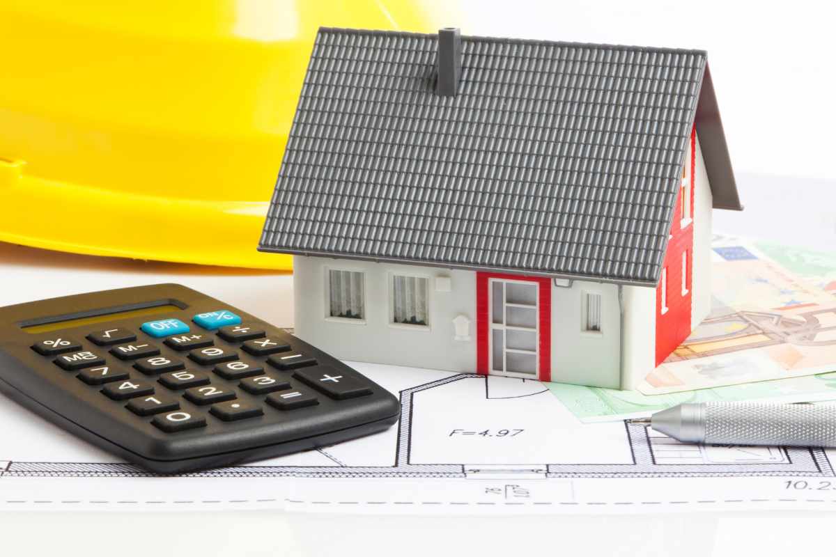 casa in miniatura su tavolo con banconota 50 euro penna e calcolatrice