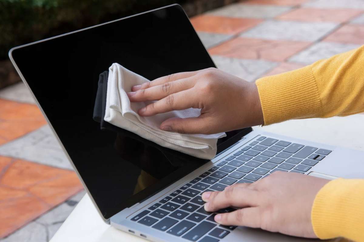 Persona che pulisce schermo del PC con un panno