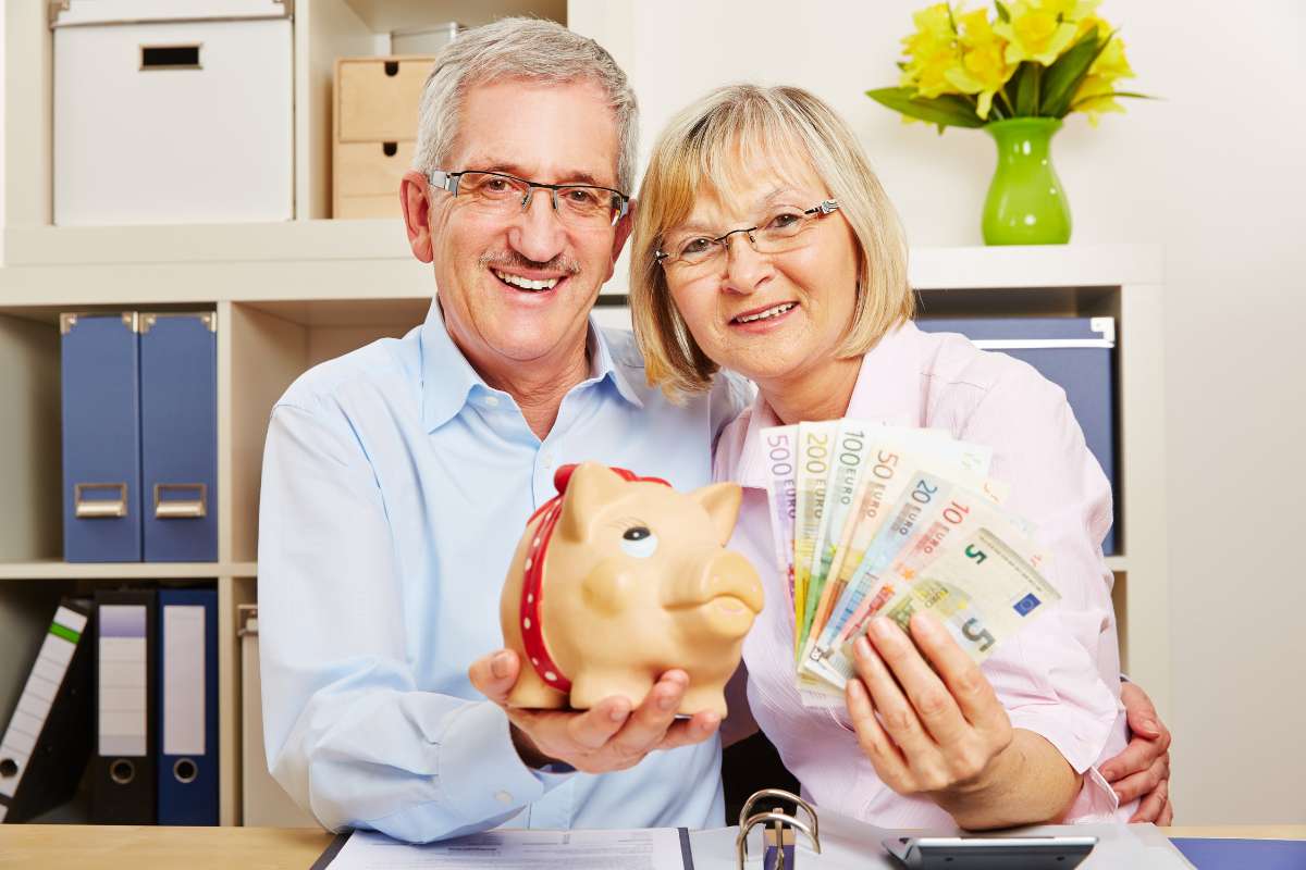 coppia di pensionati con banconote e salvadanaio in mano