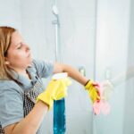 Donna che pulisce la doccia con un panno
